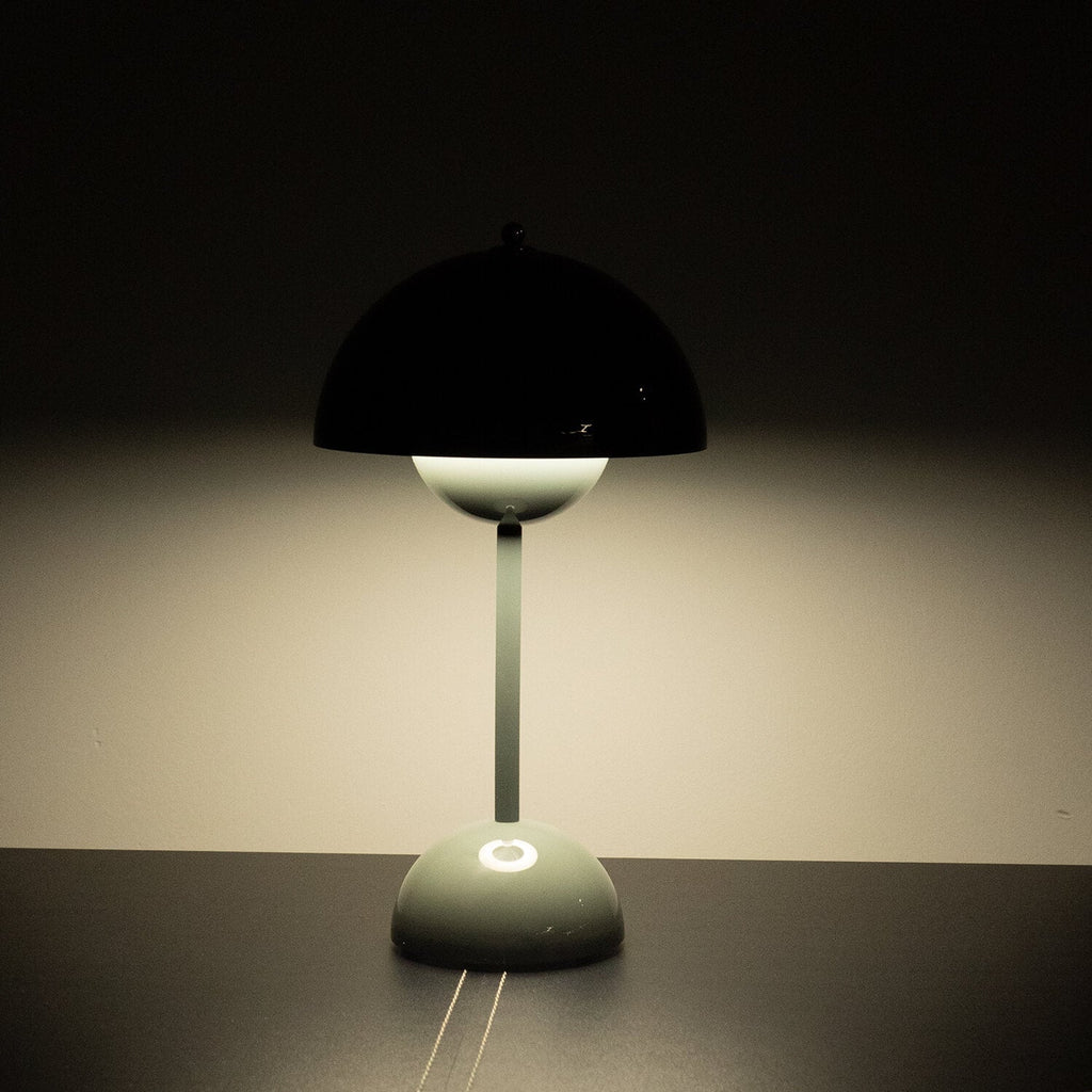 Modern table lamp with a black shade on a dark surface against a dark background
